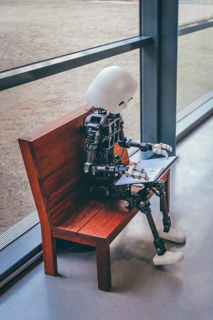 Robot humanoïde assis sur un banc, explorant des outils d’intelligence artificielle pour les débutants.